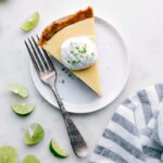 Slice of creamy key lime pie with a dollop of whipped cream on top.