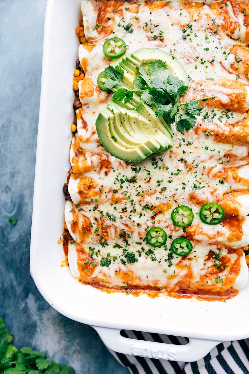 Vegetarian enchiladas fresh out of the oven, in the pan, garnished with avocado and cilantro.