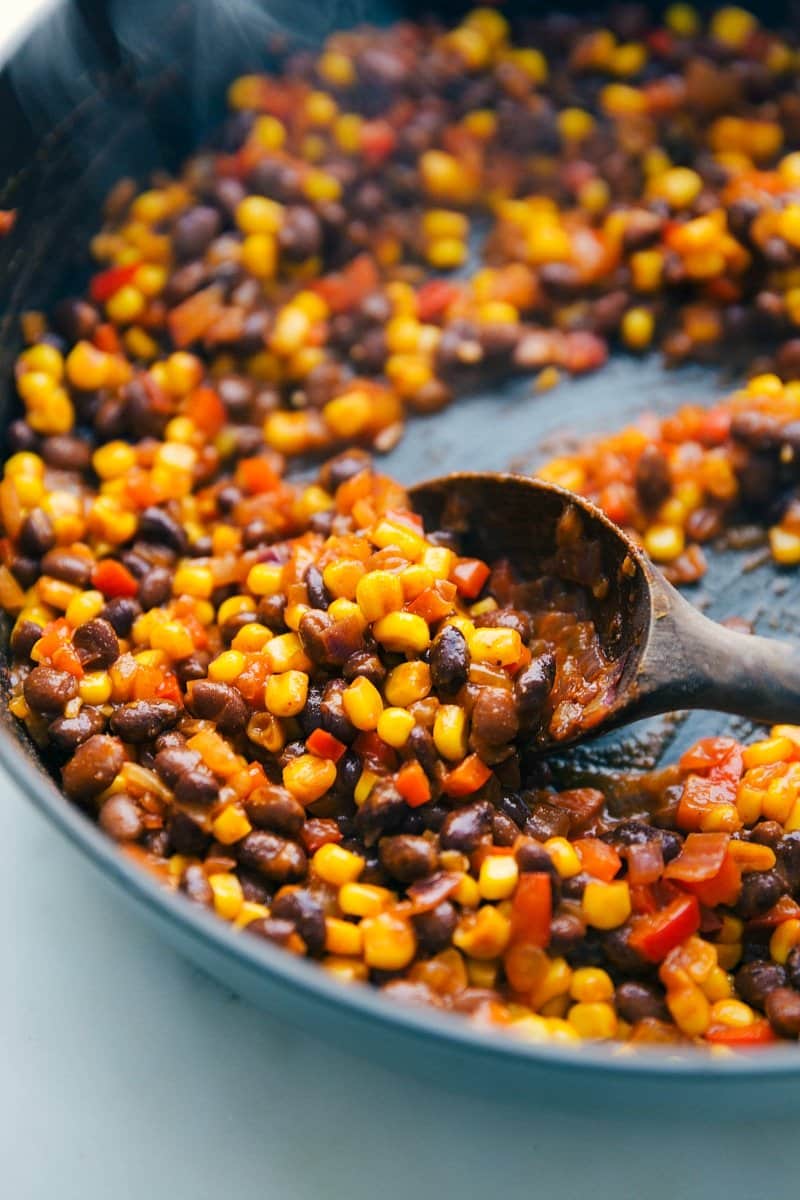 Cooking the vegetarian stuffing, including beans and vegetables, for the vegetarian enchilada recipe.