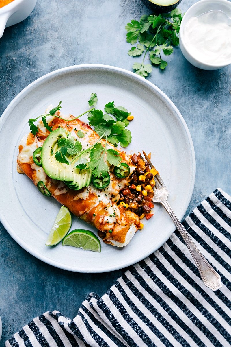 Easy vegetarian enchiladas on a plate with one cut open to reveal the tasty ingredients.