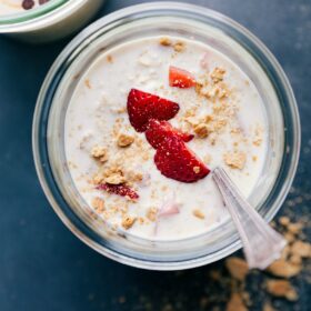 Finished strawberry cheesecake overnight oats, topped with fresh strawberries, ready for a delicious breakfast.