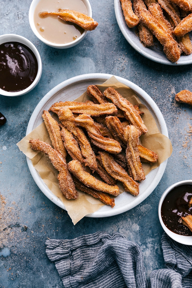 Overhead image of Churros piled on a plate with dipping sauces on the side.