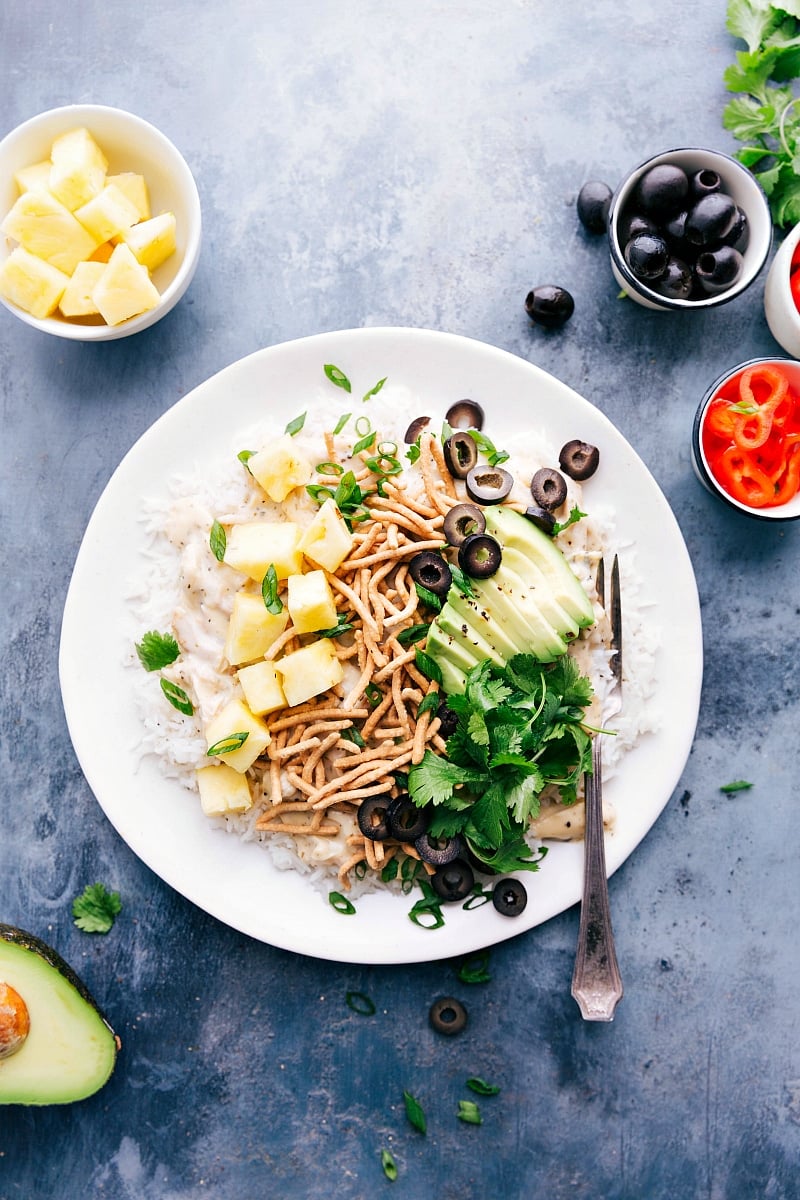 Hawaiian haystacks, a plate loaded with salad bar toppings, surrounded by additional ingredients.