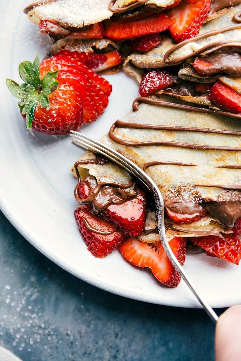 Up-close image of a crepe being cut with a fork.