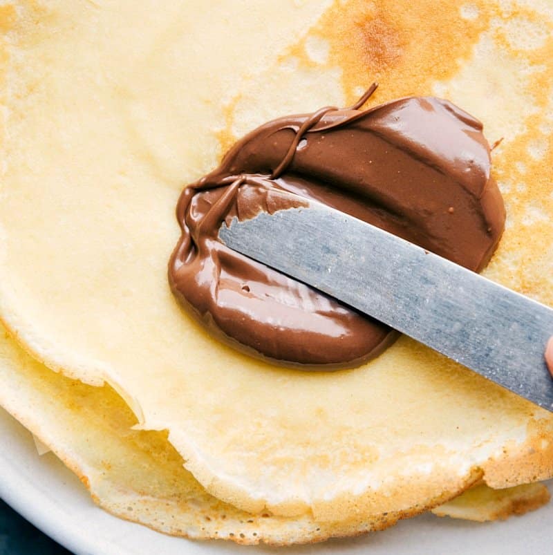 Image of Nutella being spread on a crepe.