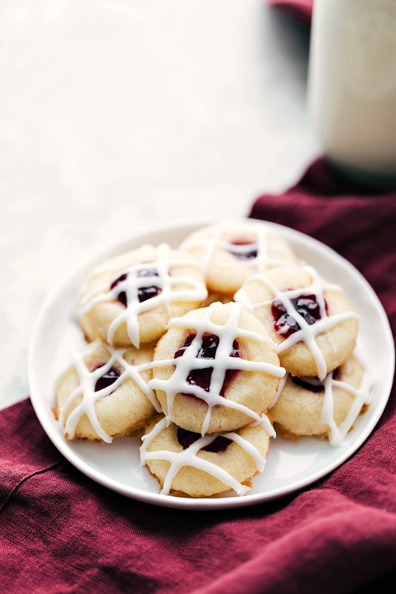 Plate of raspberry thumbprint cookies with glass of milk in background