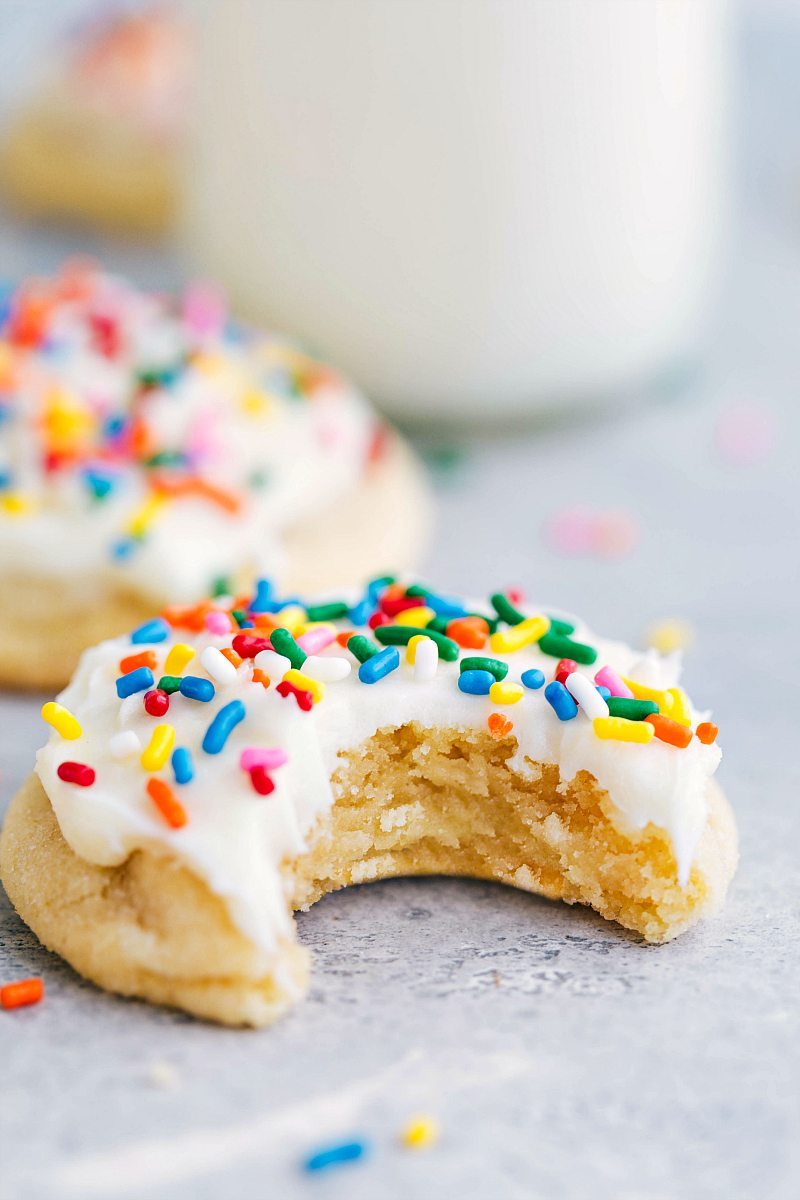 The finished soft sugar cookie recipe, featuring a delicious cookie with a thick layer of frosting on top, and a tempting bite taken out.