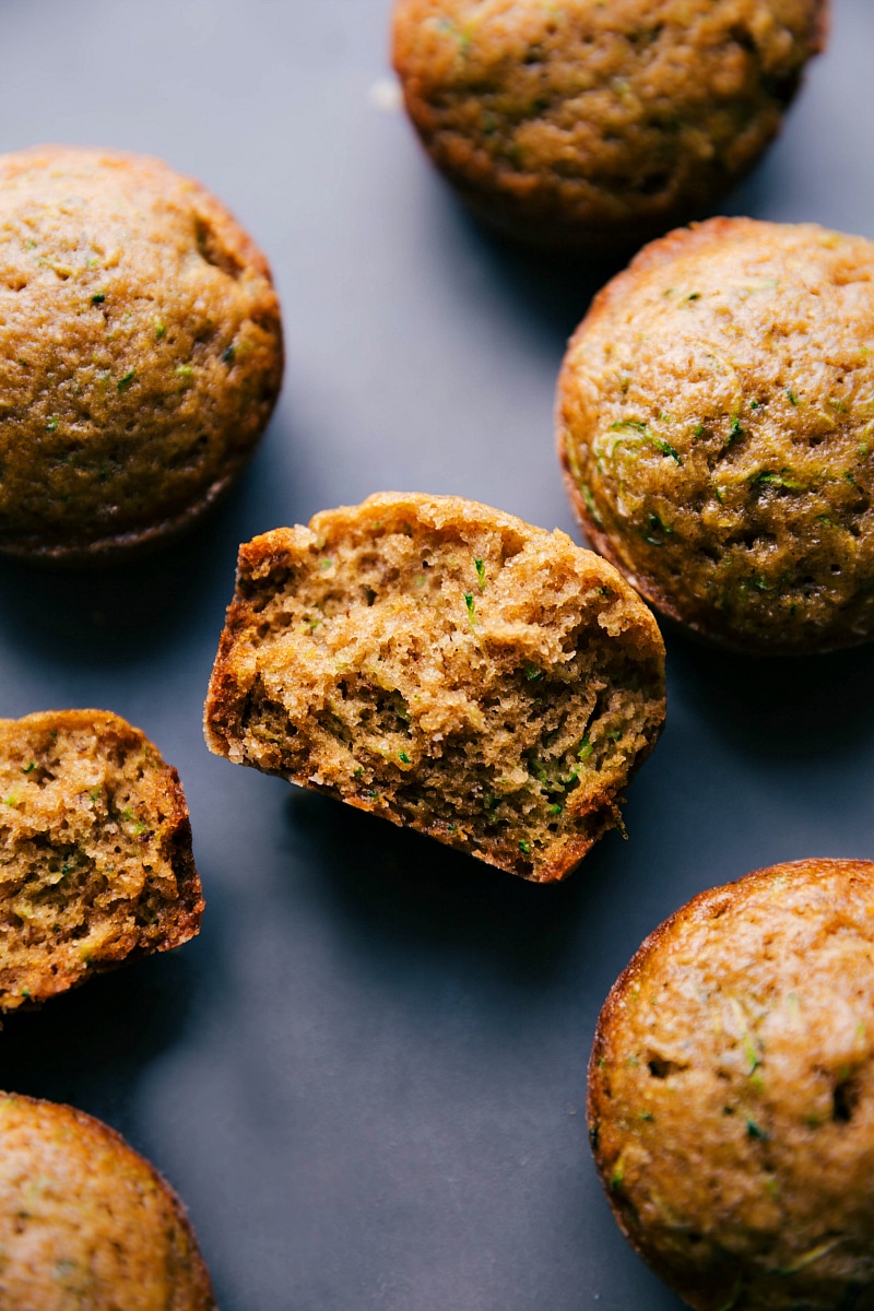 View of Healthy Zucchini Muffins, with one split in half to show the inside.