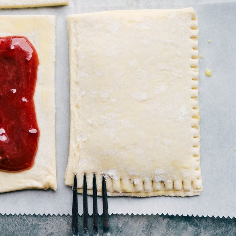 Process shot-- image of the puff pastry layers being sealed with a fork pushing down the edges.
