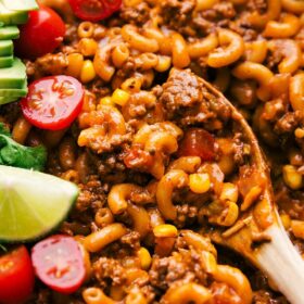 Spoon scooping up cheesy taco pasta with visible cheese and seasoned meat.