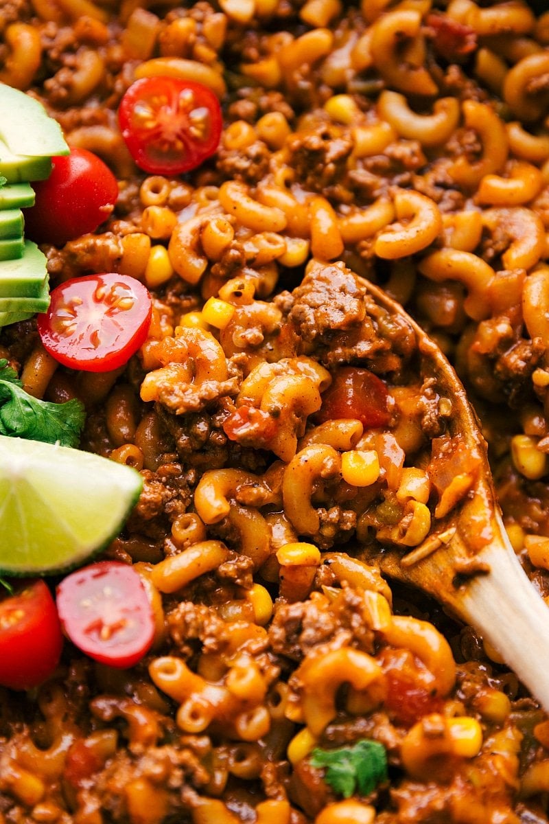 Spoon scooping up cheesy taco pasta with visible cheese and seasoned meat.