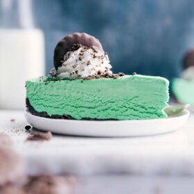 Thin mint cheesecake topped with whipped cream and a cookie garnish.