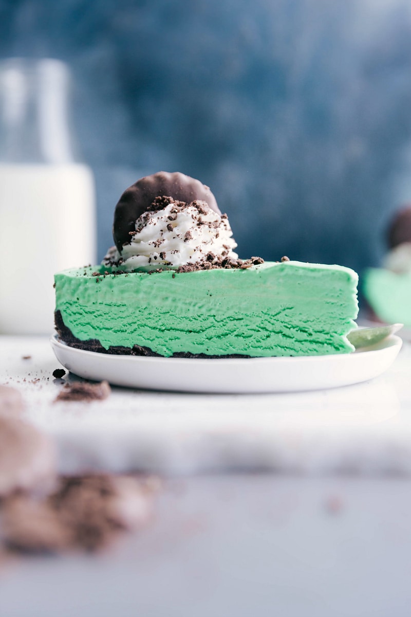 Thin mint cheesecake topped with whipped cream and a cookie garnish.