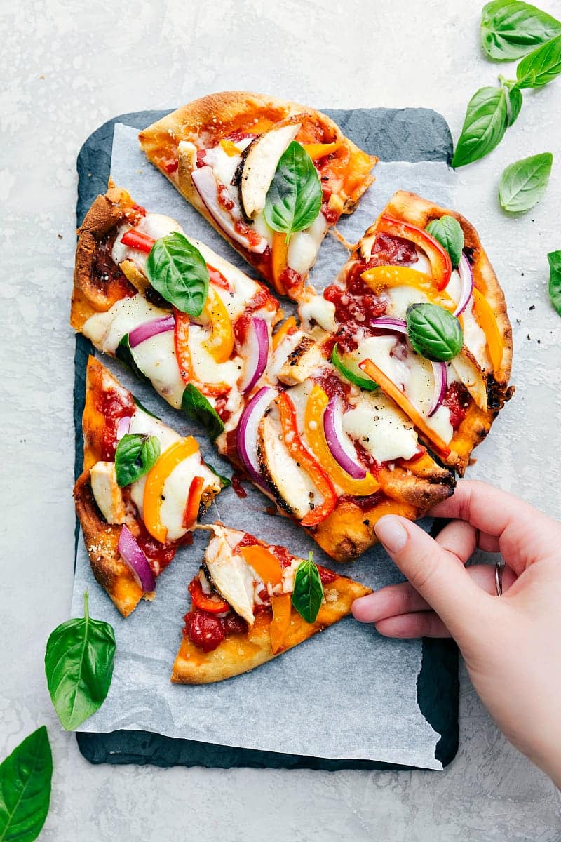 Someone taking a slice of the flatbread being pulled out.