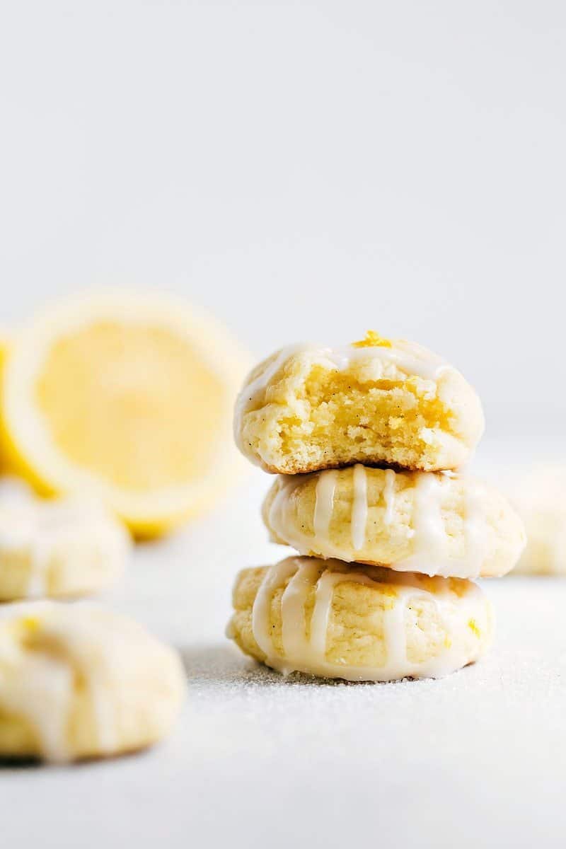 Stacked Lemon Cheesecake Cookies with a Bite Taken Out of One A stack of three lemon cheesecake cookies topped with a delicious frosting with a bite taken from the top cookie.