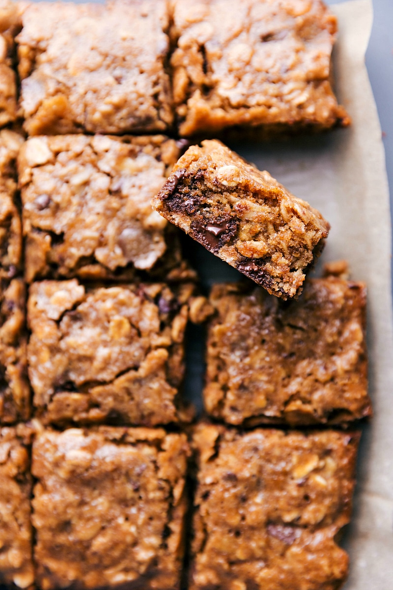 Soft baked oatmeal breakfast bars with one bar tilted up to reveal the flavorful inside.