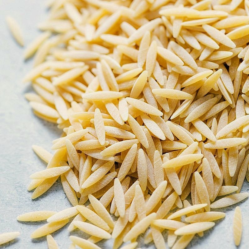 Uncooked orzo pasta spilled out, ready to be cooked.