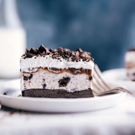 Slice of oreo ice cream cake with distinct creamy and cookie layers on a plate ready to be enjoyed.