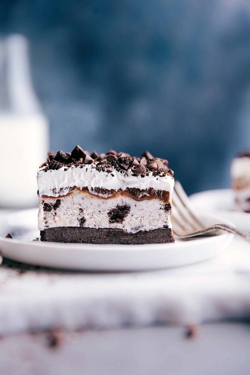 Slice of oreo ice cream cake with distinct creamy and cookie layers on a plate ready to be enjoyed.