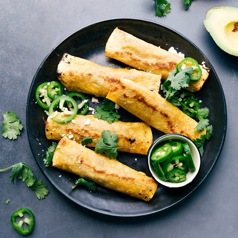 Overhead image of Pork Taquitos with fresh cilantro and jalapeños around.