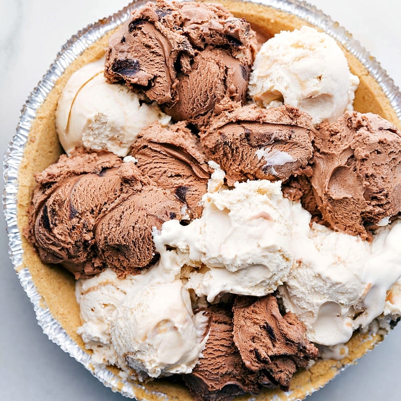 Scoops of chocolate and caramel ice cream arranged in the crust, ready to be frozen.