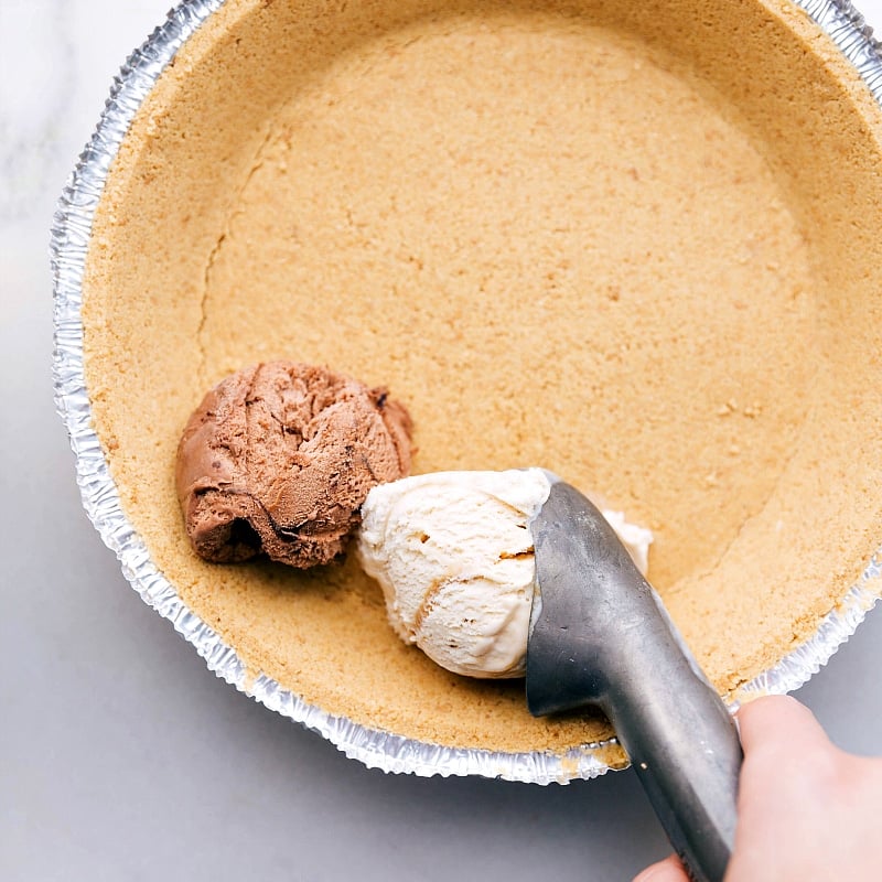 Chocolate and caramel ice cream being scooped into the crust for this Ice Cream Pie recipe.