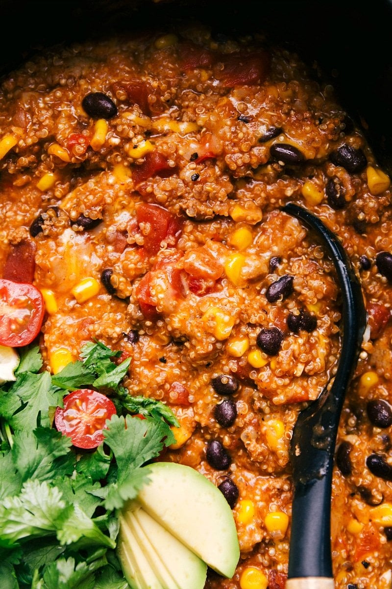 Finished enchilada quinoa dish in a crockpot, rich and flavorful, with a spoon nestled inside, ready for serving.