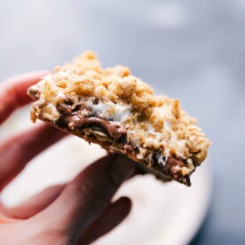 Holding a s'mores cookie bar, displaying its gooey and irresistible inside.