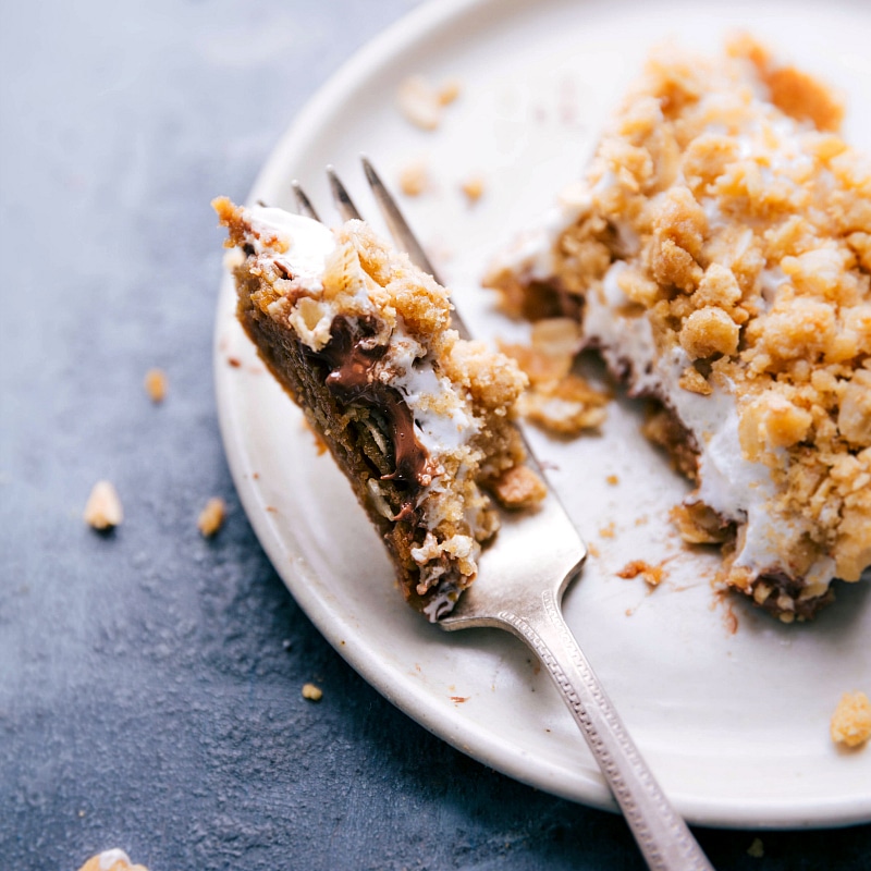 Image of a fork taking a bite out of one of the S'mores Cookie Bars.