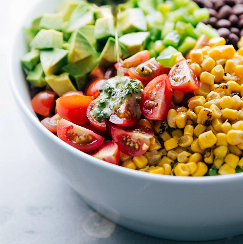 Cilantro lime dressing being poured over the colorful quinoa southwest salad, adding a burst of flavor and freshness to the dish.