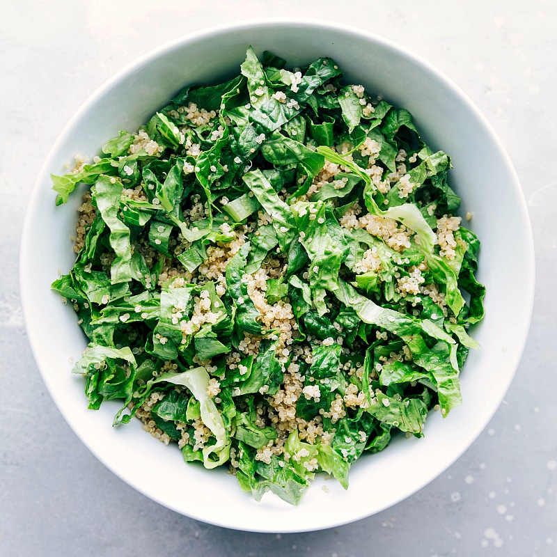 Process shot-- Image of the lettuce and quinoa being added to a bowl for this Southwest Quinoa Salad.