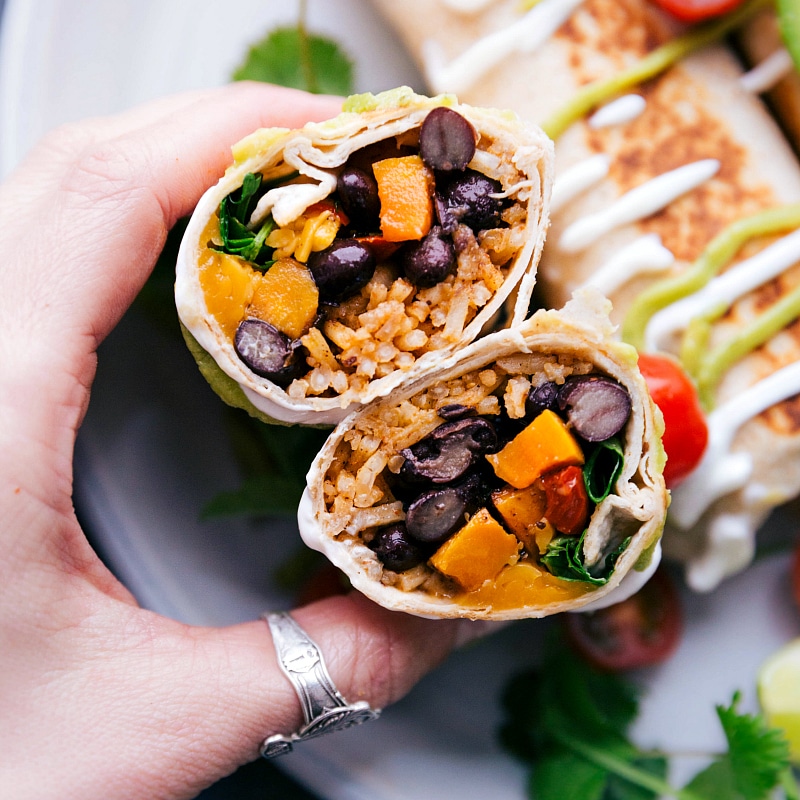 Cutting the meal in half to display the filling with beans, sweet potatoes, and rice spilling out.