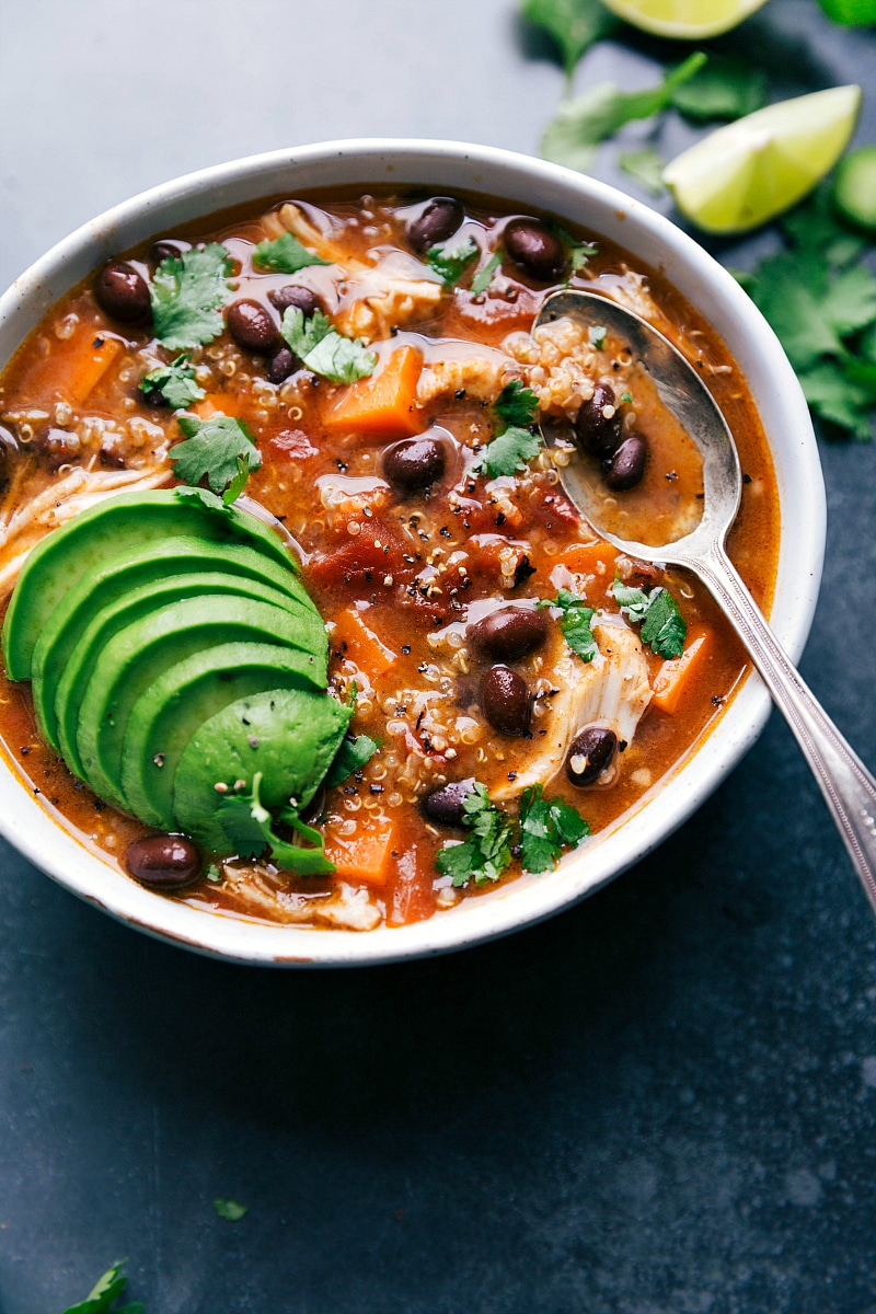 A bowl of sweet potato chicken soup, topped with fresh herbs and avocados, ready to be enjoyed as a delicious and wholesome meal.