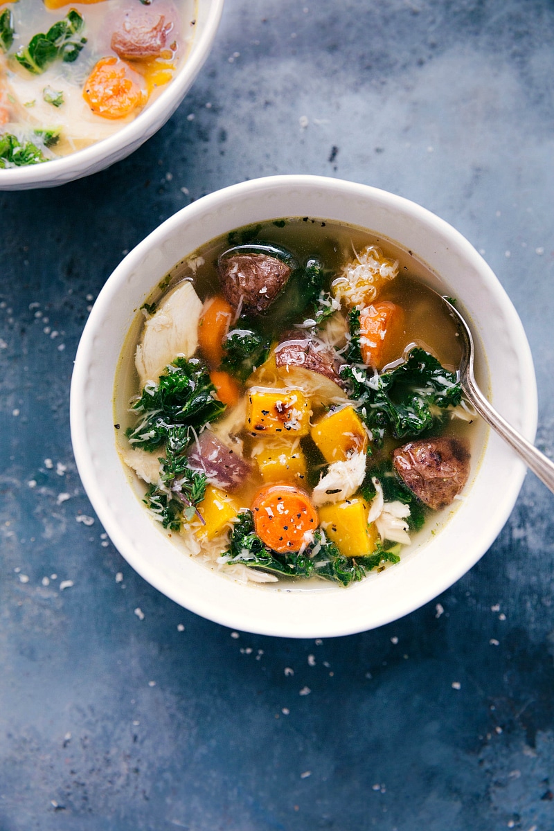 Bowl of chicken and vegetable soup, with a spoon on the side, ready to be enjoyed.