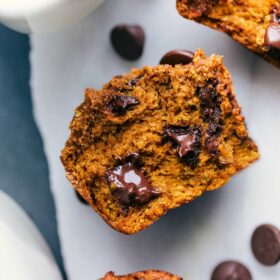 Healthy pumpkin muffin split open to reveal the soft and moist interior with melting chocolate chips, ready to be eaten.