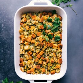 Cornbread dressing fresh out of the oven, garnished with fresh herbs.