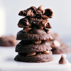 Stacked fudge brownie cookies with one split in half to reveal their rich and gooey inside.