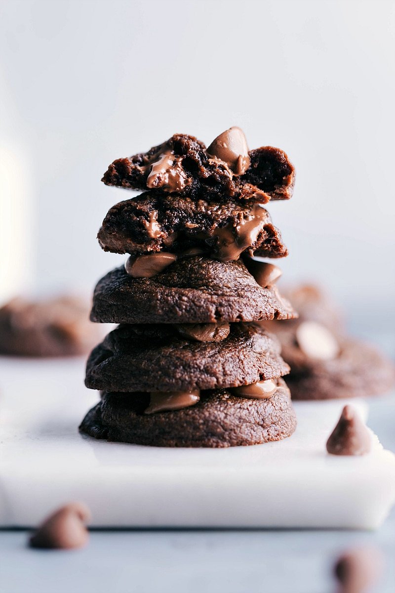 Stacked fudge brownie cookies with one split in half to reveal their rich and gooey inside.