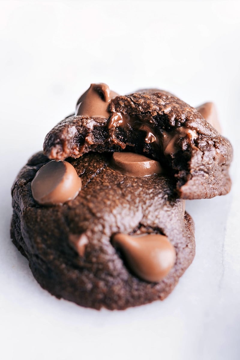 Freshly baked fudge brownie cookies, chocolatey and tempting, with a bite taken out.