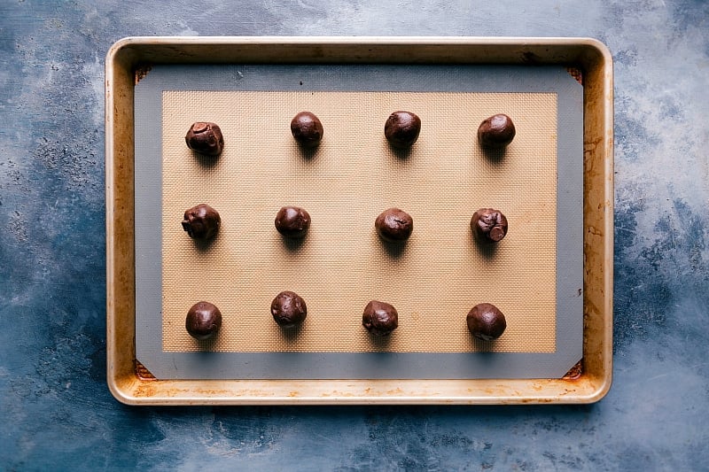 Uniformly rolled cookie dough balls for the fudge brownie cookies, ready for baking.