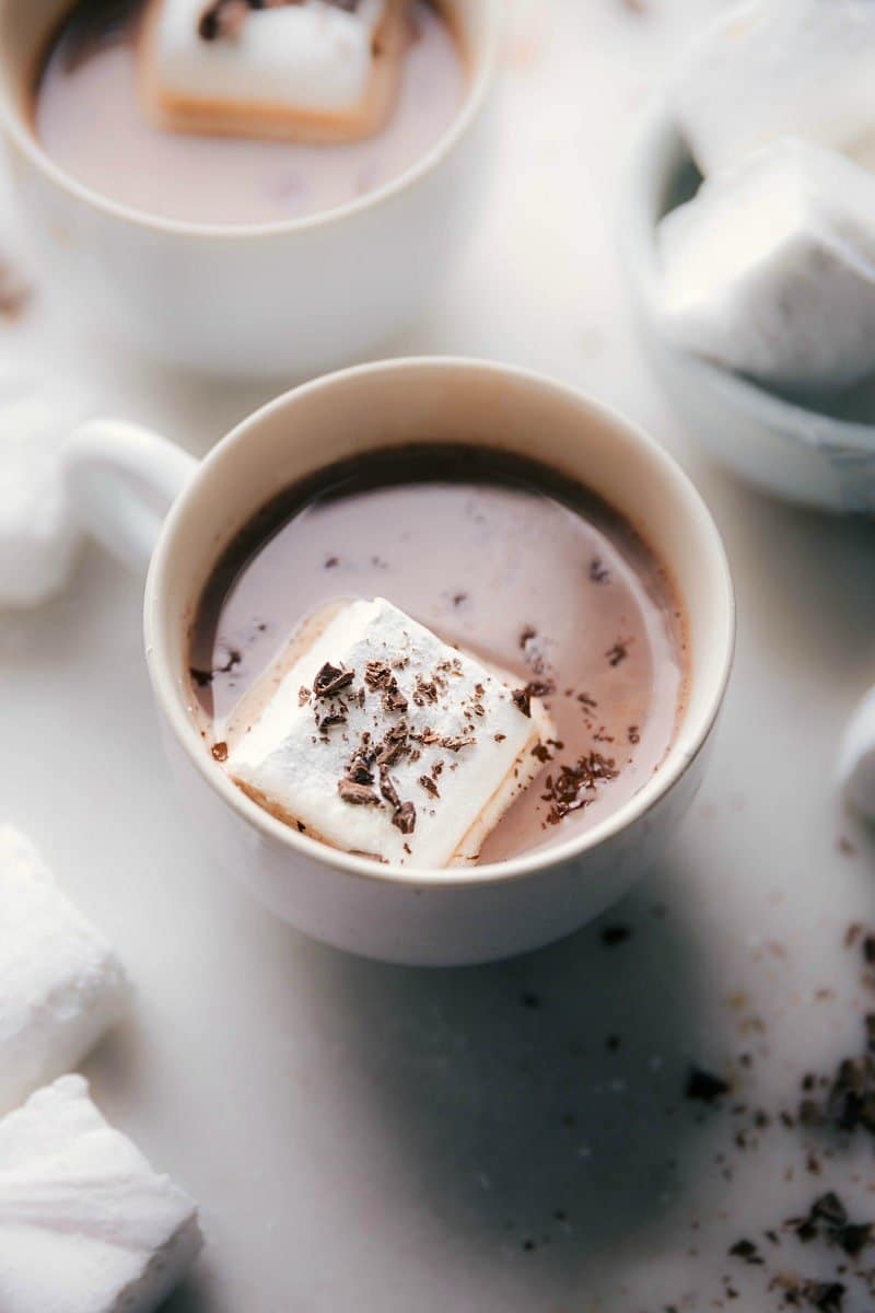 Homemade marshmallows floating in a cup of hot chocolate, topped with chocolate shavings.