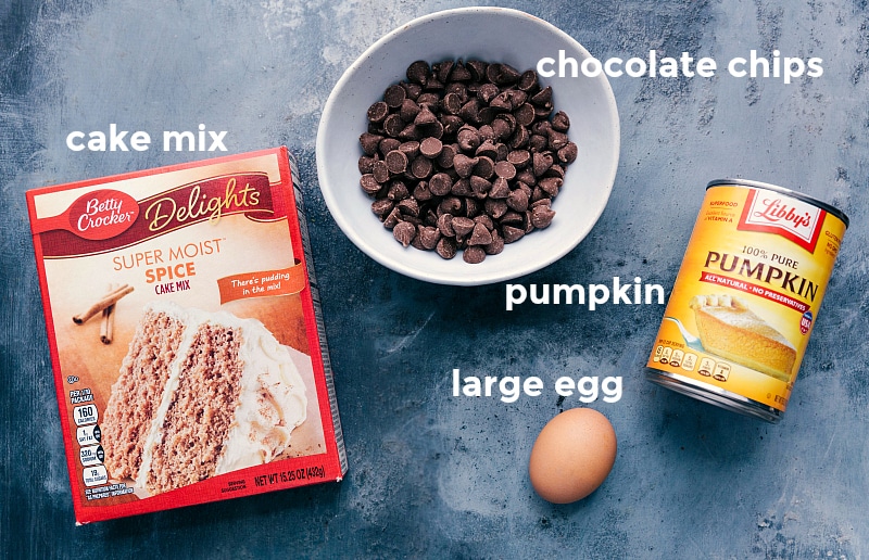 Ingredients laid out, including a box of cake mix, chocolate chips, a can of pumpkin puree, and an egg.