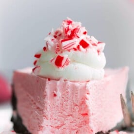 Slice of no-bake peppermint cheesecake with a bite missing, showcasing its creamy texture and peppermint layers.