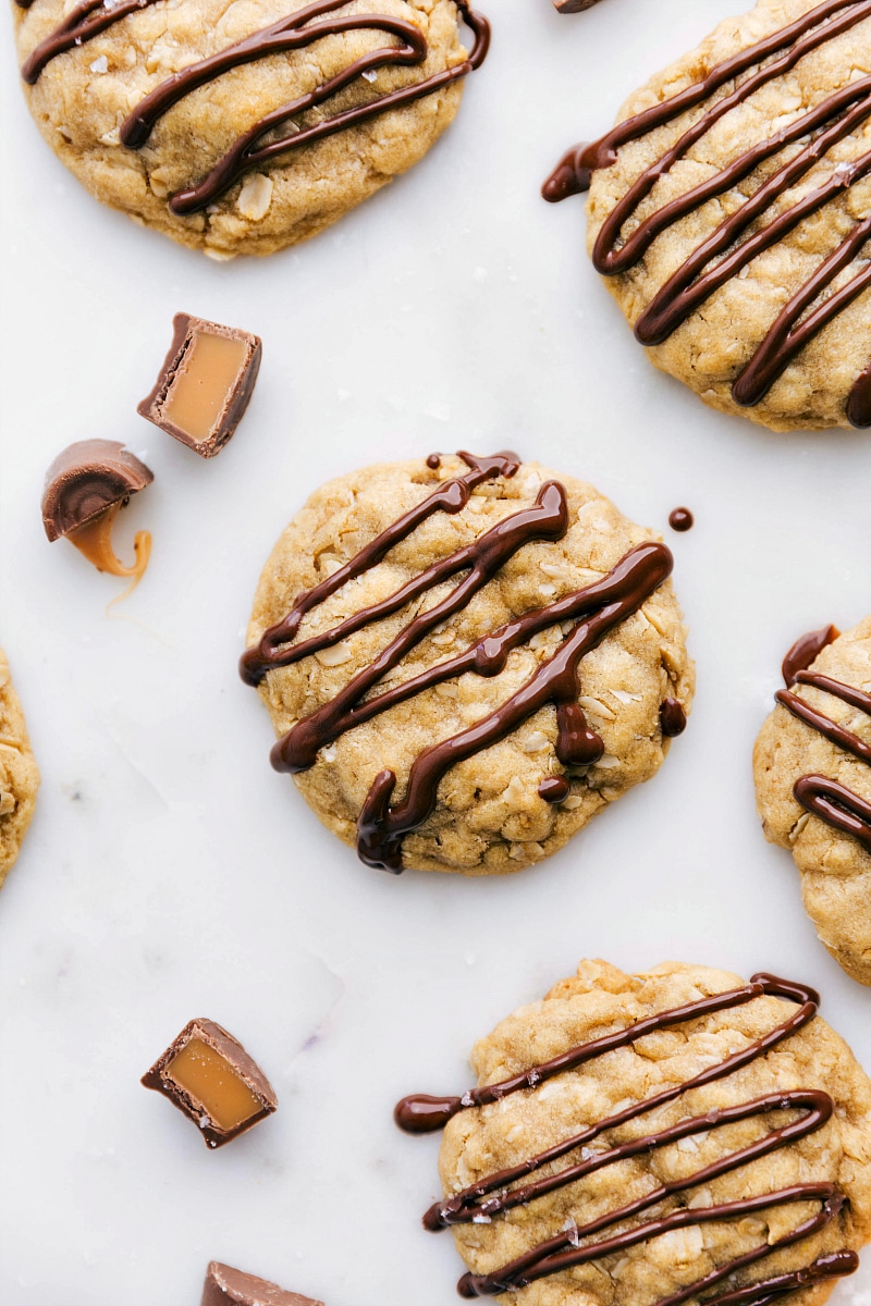 Baked, ready-to-eat salted caramel oatmeal cookies with a drizzle of chocolate on top, showcasing their delicious and indulgent appearance.