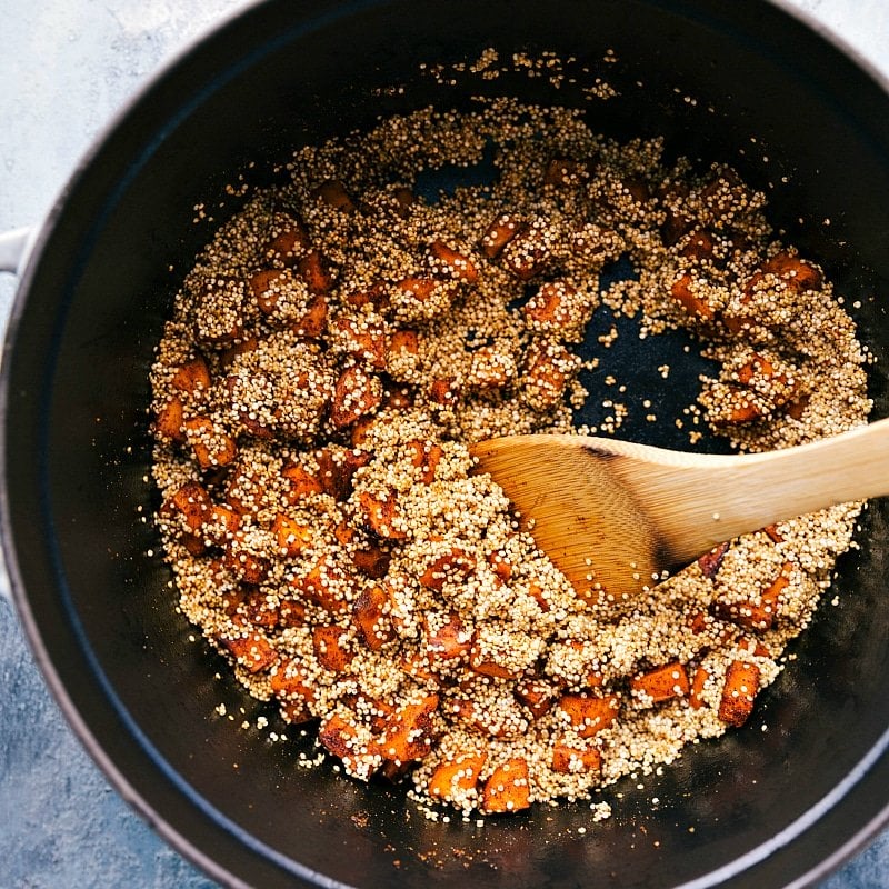 Quinoa being added to the pot with the already sautéed sweet potatoes, combining for the chili recipe.