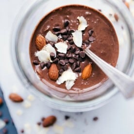 Almond joy overnight oats in a bowl, deliciously topped with almonds, shredded coconut, and chocolate chips.