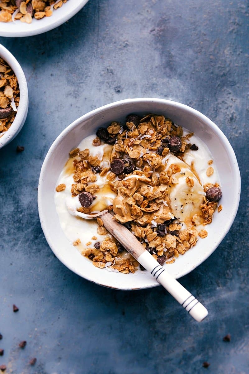 Overhead image of Peanut Butter Granola in a bowl of yogurt with a spoon on the side.