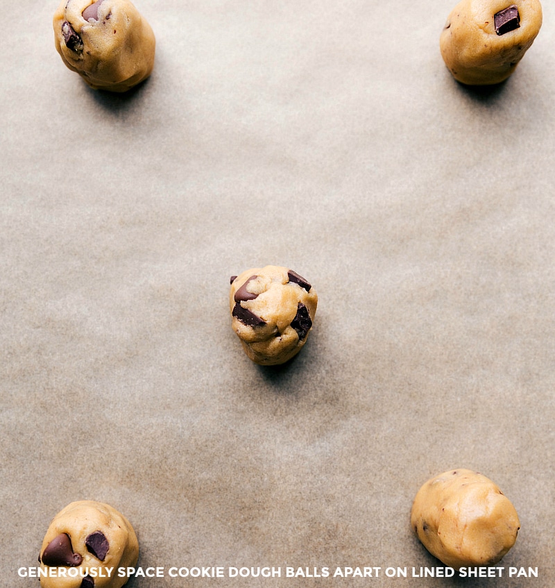 Dough balls arranged on a sheet pan lined with parchment paper.