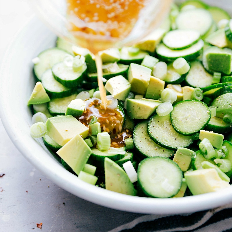 Image of the dressing being added to Asian Cucumber Salad.