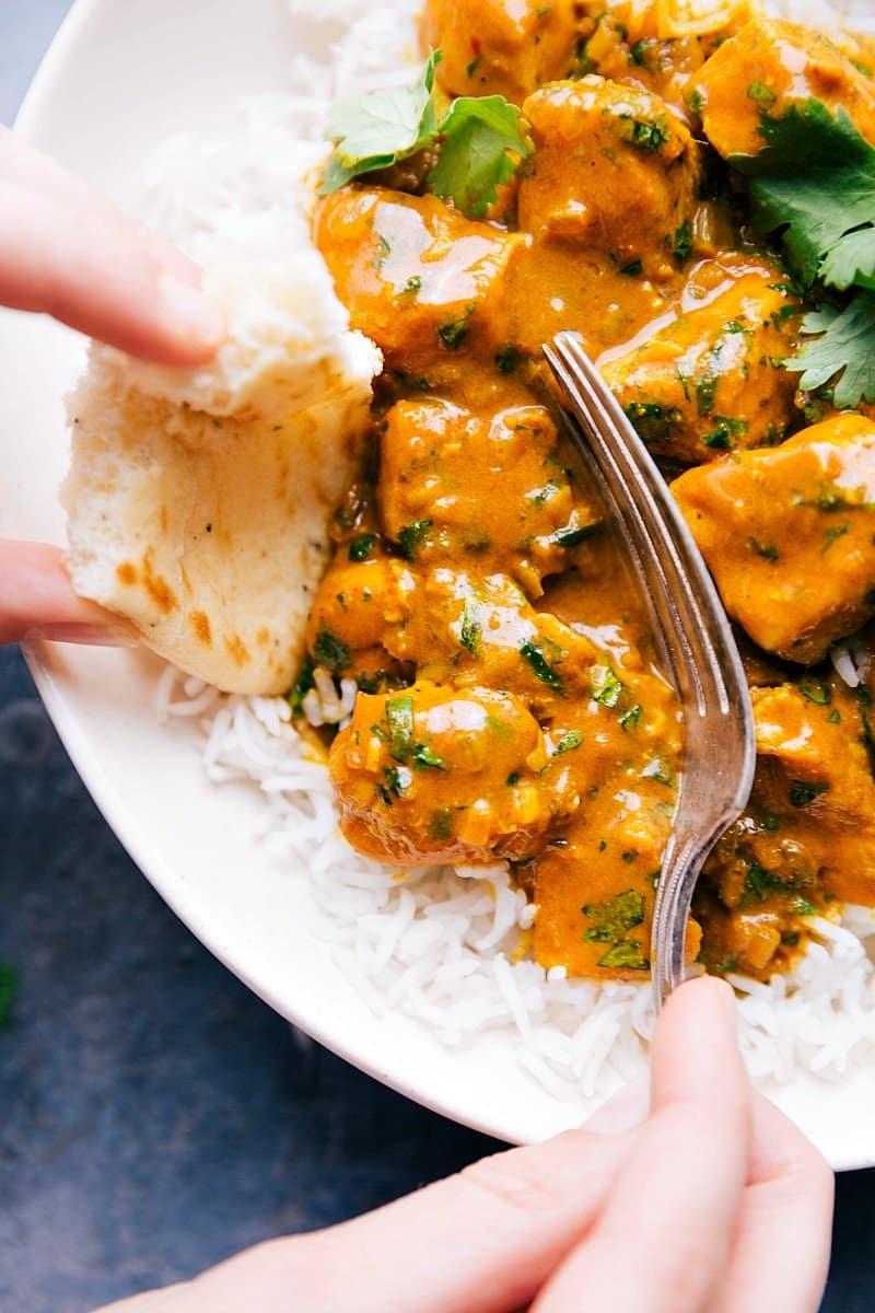 Up-close image of Curry Chicken being scooped up with a fork and naan bread.